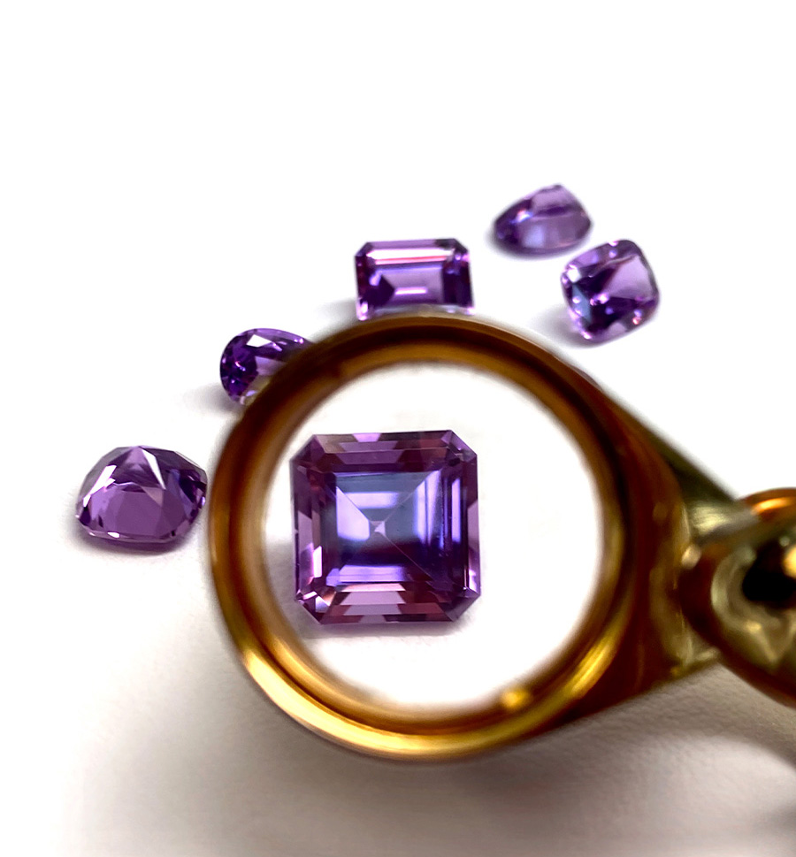 Chatham lab grown purple sapphire magnified by a loupe