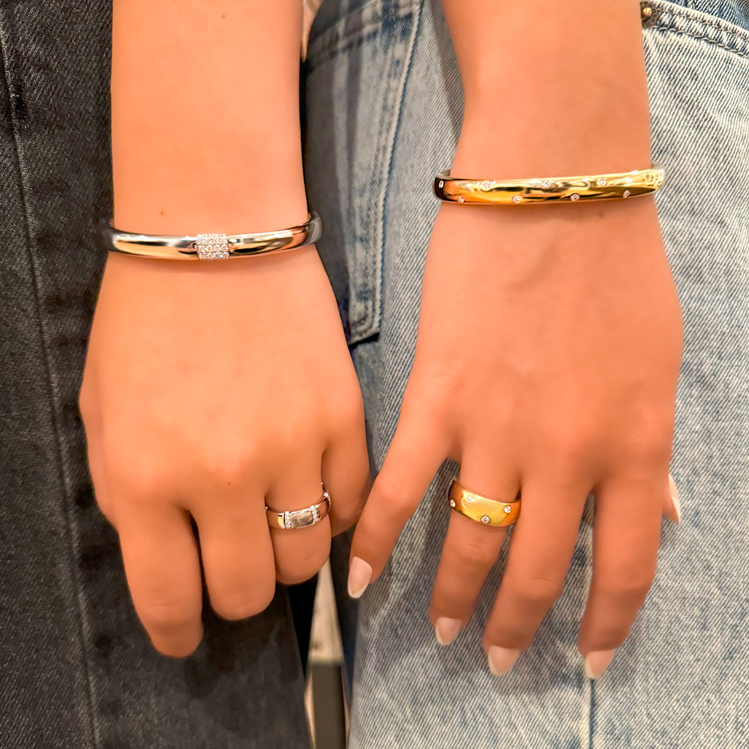 Two hands with one wearing a 14K white gold Chatham lab grown diamond cuff and ring and the other wearing a 14K yellow gold lab grown diamond cuff and matching ring